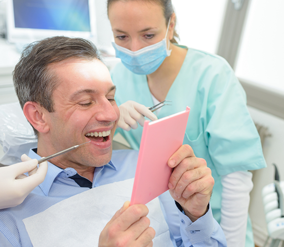 Man checking smile in handheld mirror