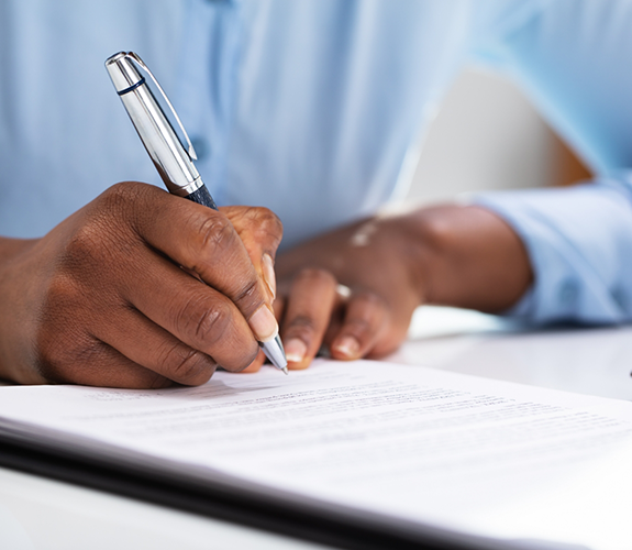 Close-up of person using pen to fill out form