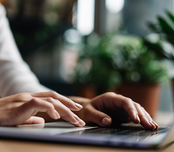 Close-up of hands typing on laptop