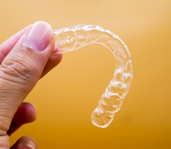 Close-up of hand holding clear aligner