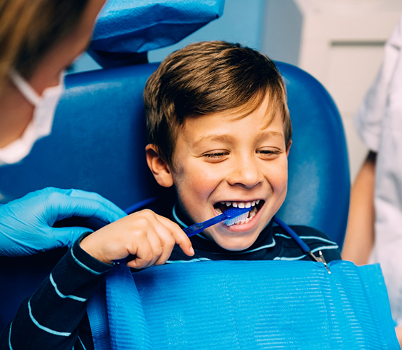 Little boy brushing his teeth in dental chair