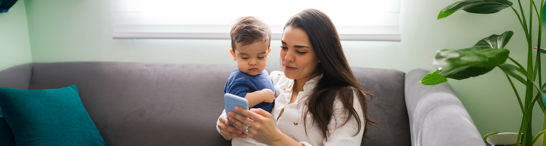 Woman using cell phone while holding baby