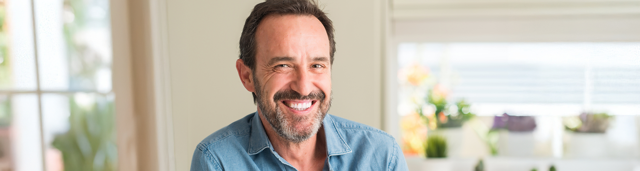 Bearded man sitting in kitchen smiling